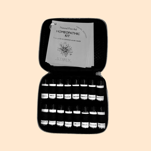 Homeopathic kit with bottles and a guide on a gray surface.